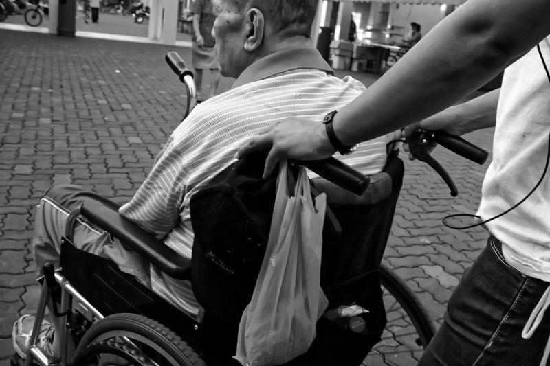 Persona llevando a otra en silla de ruedas